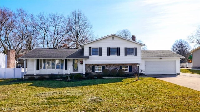 split level home featuring a front yard, fence, an attached garage, a chimney, and concrete driveway