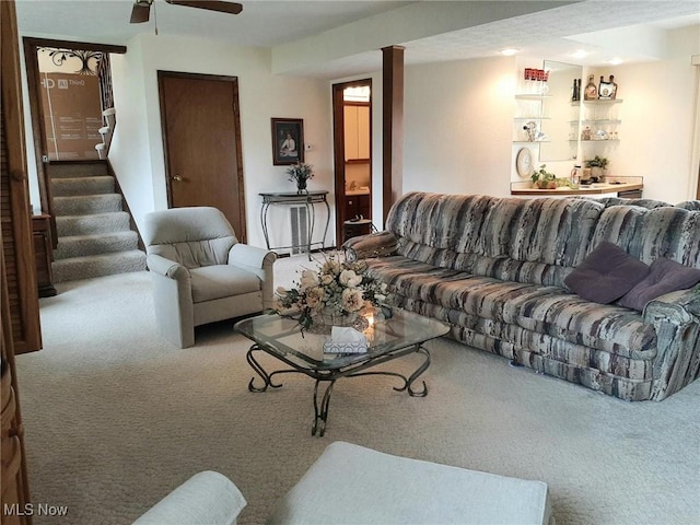 carpeted living area featuring stairway and a ceiling fan