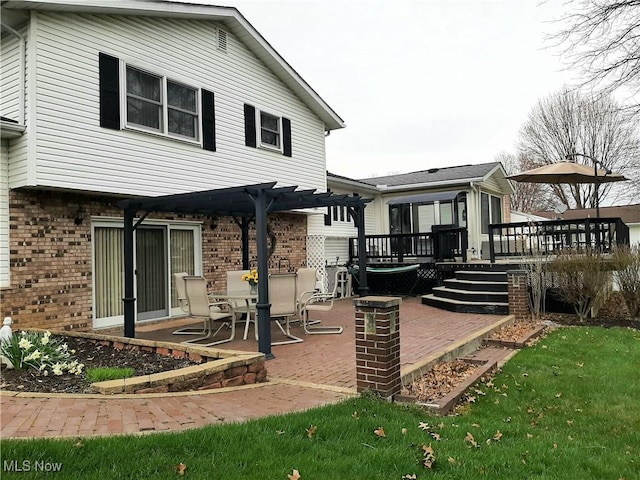 back of house featuring a patio, a deck, and brick siding