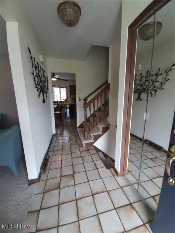 entryway featuring stairway, baseboards, a ceiling fan, and light tile patterned flooring