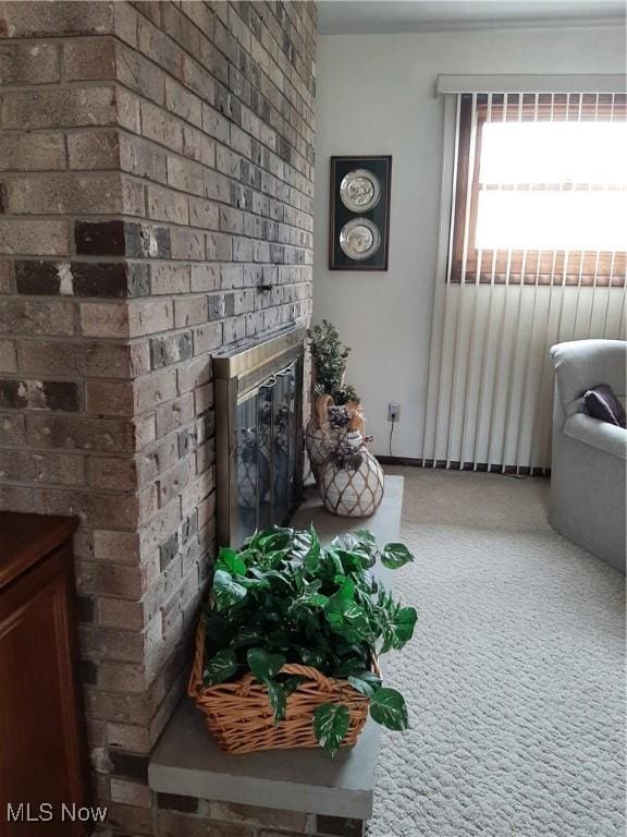 carpeted living room with brick wall and a brick fireplace