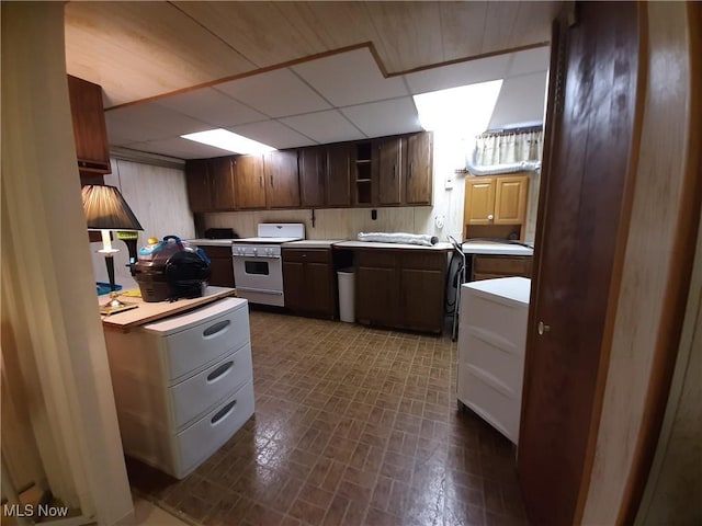 kitchen featuring open shelves, brick patterned floor, light countertops, white range oven, and a paneled ceiling