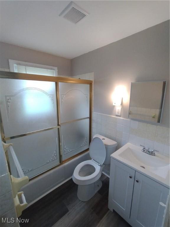 181 E Judson Ave, Youngstown, OH 44507 - full bath featuring wood finished floors, vanity, shower / bath combination with glass door, tile walls, and toilet