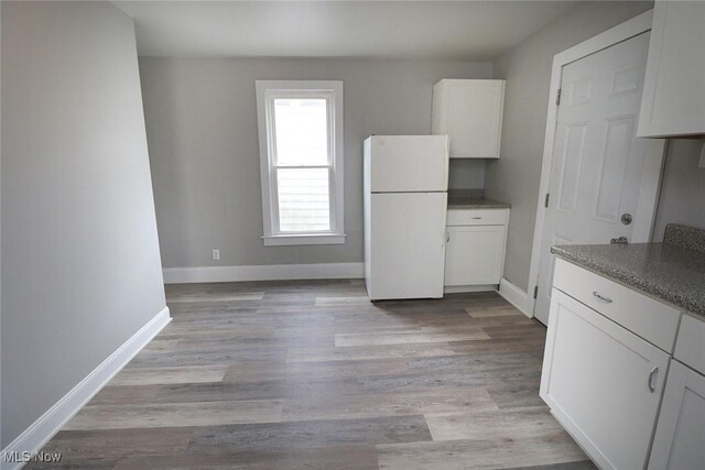 kitchen featuring white cabinets, freestanding refrigerator, baseboards, and light wood finished floors