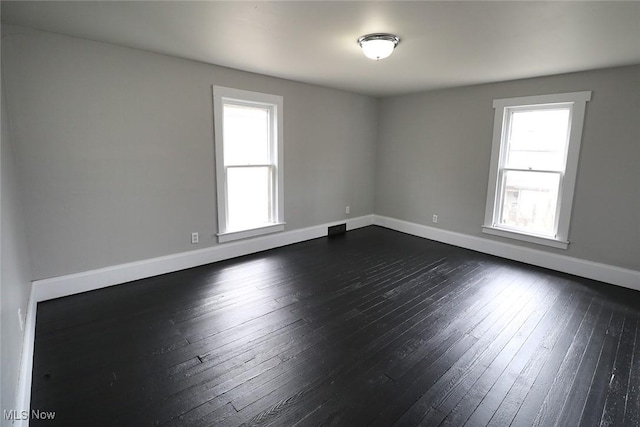 empty room with baseboards and dark wood finished floors