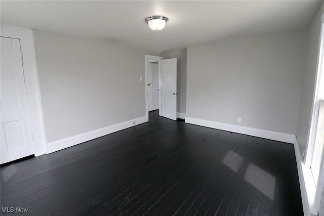 empty room with dark wood-type flooring and baseboards