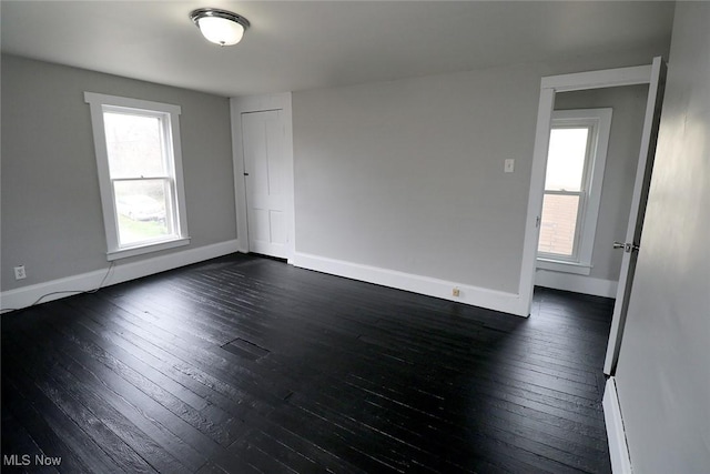 spare room with dark wood-type flooring and baseboards