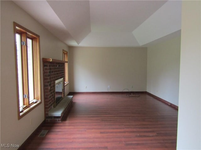 230 Bryden Rd, Weirton, WV 26062 - unfurnished living room with visible vents, baseboards, a brick fireplace, a tray ceiling, and wood finished floors