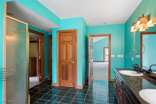 full bath with tile patterned flooring, double vanity, a textured ceiling, and a sink