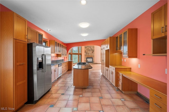 kitchen with appliances with stainless steel finishes, recessed lighting, glass insert cabinets, and a kitchen island