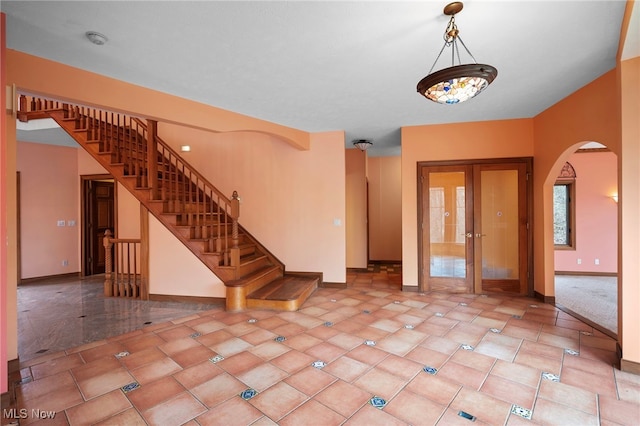 spare room with baseboards, stairway, arched walkways, and tile patterned flooring