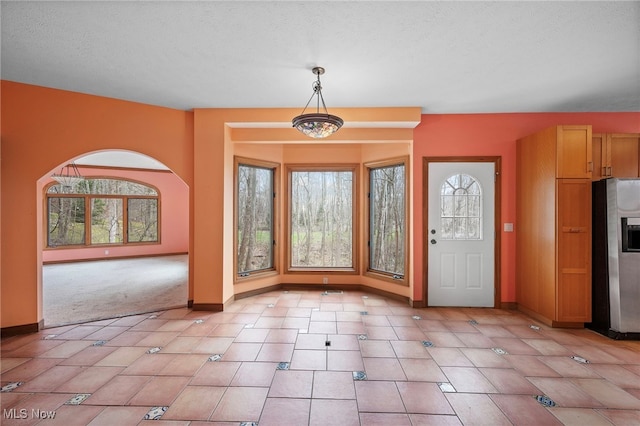 foyer entrance with light tile patterned floors, baseboards, and a textured ceiling