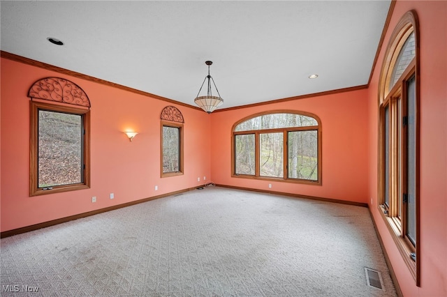 spare room featuring carpet flooring, visible vents, baseboards, and ornamental molding