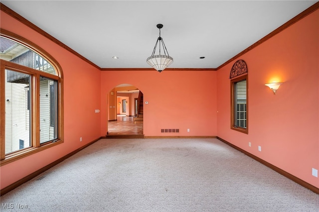 carpeted empty room featuring visible vents, baseboards, arched walkways, and a wealth of natural light