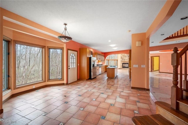 kitchen featuring stainless steel fridge with ice dispenser, plenty of natural light, dishwasher, and baseboards