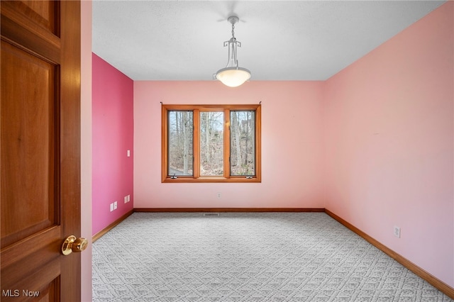 spare room featuring light colored carpet and baseboards