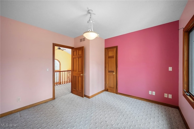 carpeted empty room featuring baseboards, a ceiling fan, and visible vents