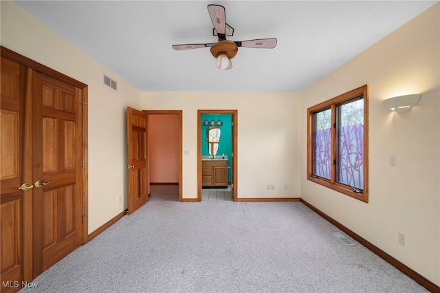 unfurnished bedroom featuring ensuite bath, visible vents, light colored carpet, and baseboards