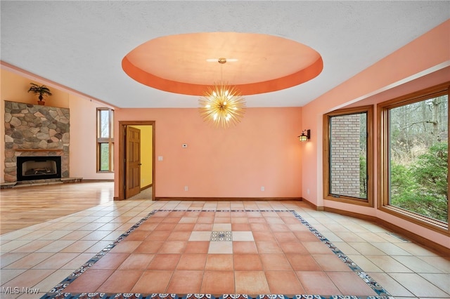 interior space with a tray ceiling, tile patterned floors, plenty of natural light, and baseboards