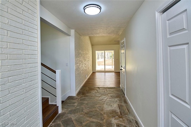 hallway featuring stone floors, stairs, and baseboards