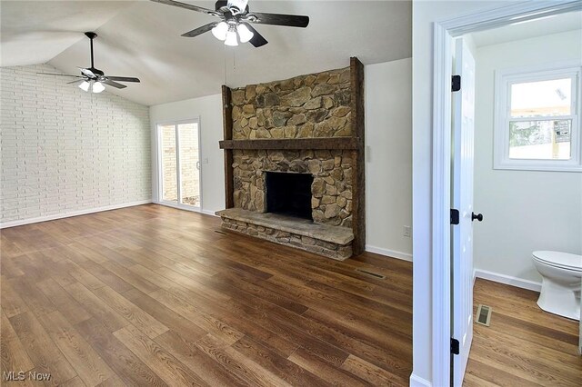 unfurnished living room with vaulted ceiling, a ceiling fan, wood finished floors, and visible vents