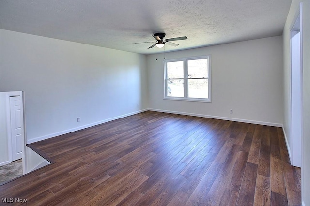 empty room featuring dark wood finished floors, a textured ceiling, baseboards, and ceiling fan
