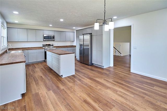 kitchen with a center island, a sink, wood counters, stainless steel appliances, and recessed lighting
