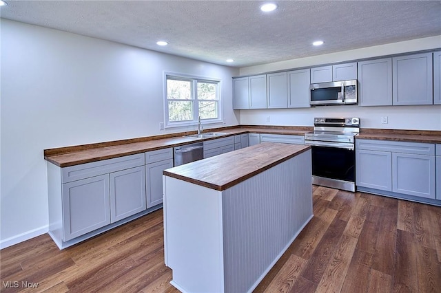 kitchen featuring recessed lighting, wooden counters, stainless steel appliances, and a sink