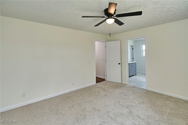unfurnished room featuring carpet, a textured ceiling, baseboards, and ceiling fan