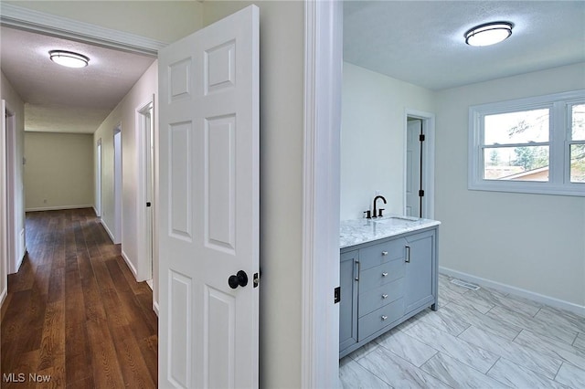 hallway with baseboards and a sink