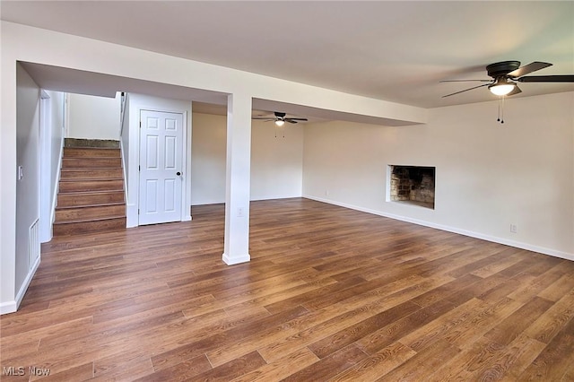 unfurnished living room featuring stairway, wood finished floors, and ceiling fan