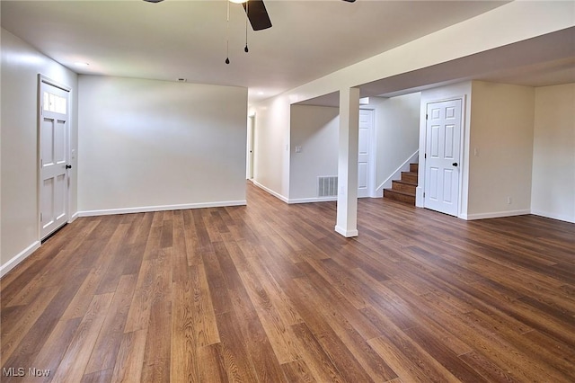 basement featuring visible vents, dark wood-type flooring, baseboards, stairs, and ceiling fan