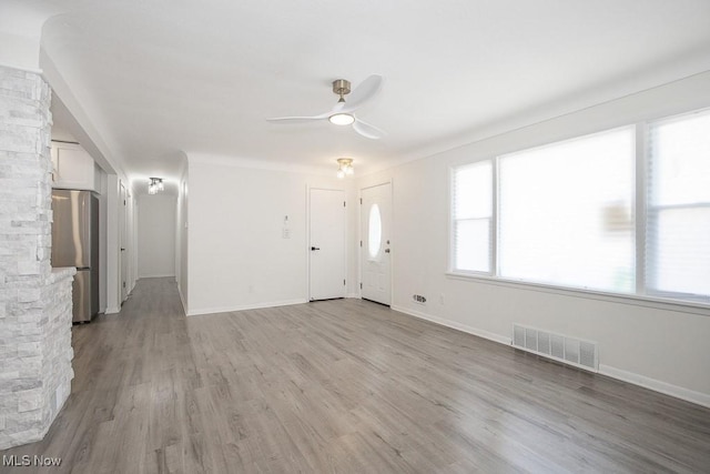 unfurnished living room featuring light wood-style flooring, baseboards, a ceiling fan, and visible vents