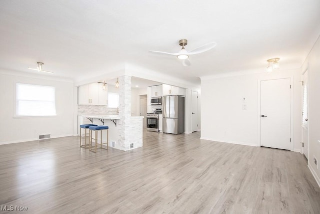 unfurnished living room featuring light wood finished floors, visible vents, baseboards, and ceiling fan
