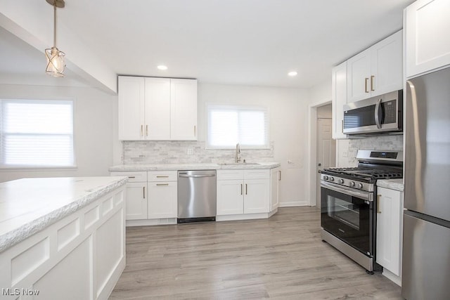 kitchen featuring stainless steel appliances, light wood-style floors, white cabinetry, and a sink