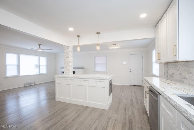 kitchen with stainless steel dishwasher, decorative columns, light wood-style flooring, visible vents, and backsplash