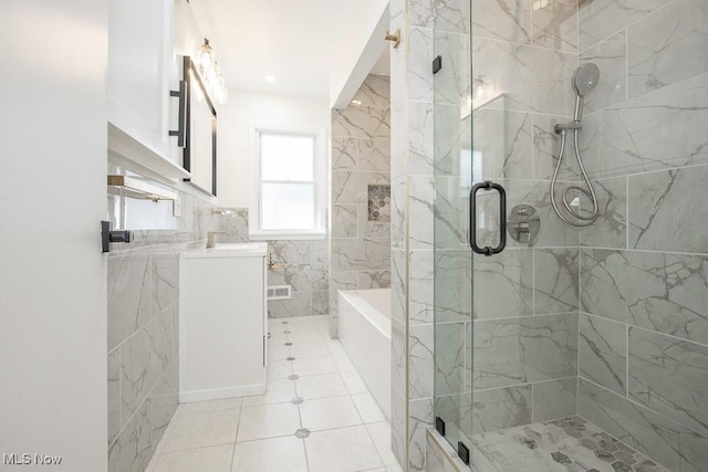 bathroom with a stall shower, a garden tub, vanity, and tile walls