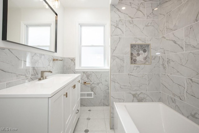 bathroom featuring vanity, a tub, tile patterned flooring, visible vents, and tile walls