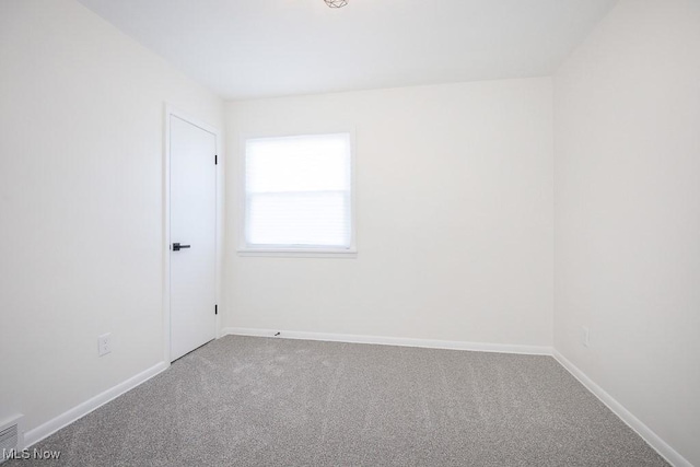 carpeted empty room featuring baseboards