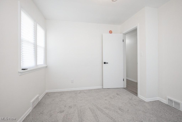 carpeted empty room with visible vents and baseboards