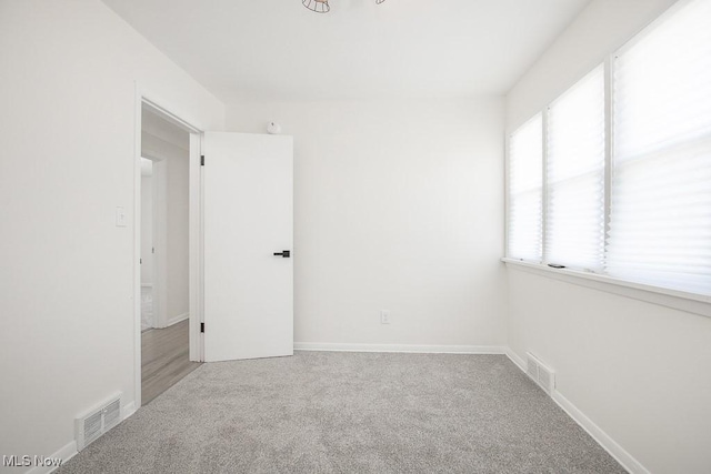 carpeted spare room featuring visible vents and baseboards