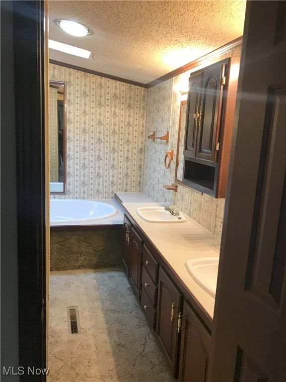 bathroom featuring a textured ceiling, wallpapered walls, and a sink