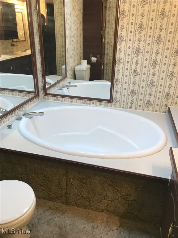full bathroom with toilet, a garden tub, vanity, and wallpapered walls