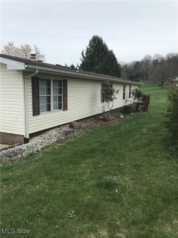 view of side of home featuring central AC unit and a lawn