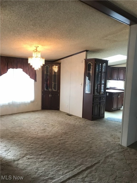empty room with a chandelier, a textured ceiling, and carpet floors