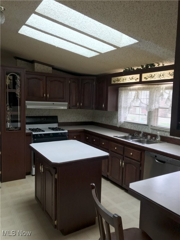 kitchen with gas range, a sink, dishwashing machine, under cabinet range hood, and light floors