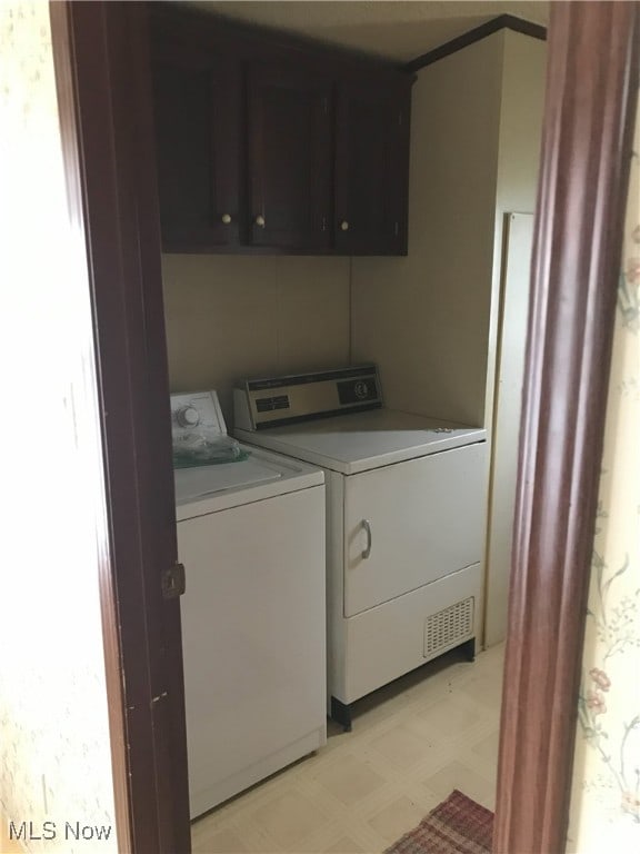laundry room featuring washer and dryer, cabinet space, and light floors