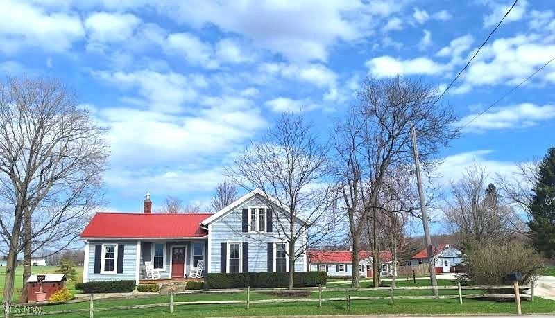 17091 Madison Rd, Middlefield, OH 44062 - view of front facade with a chimney, a fenced front yard, metal roof, and a front yard