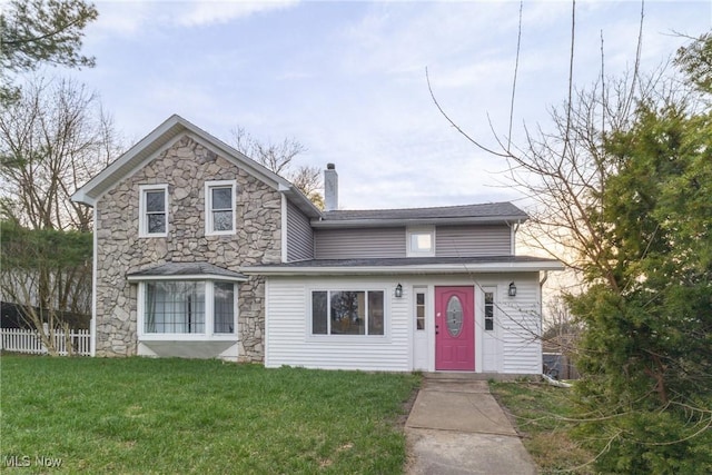 traditional-style house featuring a chimney, a front yard, stone siding, and fence