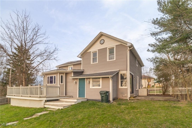 back of property with fence, a wooden deck, a patio, and a lawn